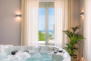 a bath tub in a room with a large window at Sampatiki Suites & Spa - Luxury Seaview Suites - Opened 2024 in Leonidio +81 photos