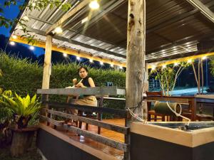 a woman sitting on a fence in a garden at GJ TOUR and HOMESTAY in Pang Mapha