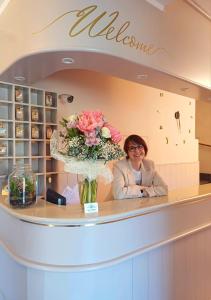 Eine Frau steht hinter einem Tresen mit einer Vase voller Blumen. in der Unterkunft Hotel Del Mera in Sorico