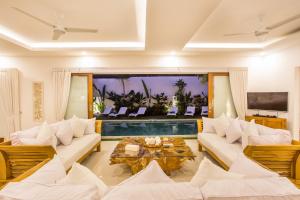 a living room with white furniture and a pool at Villa Kamboja Deluxe in Seminyak