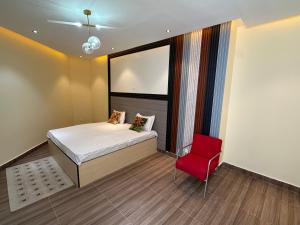 a bedroom with a bed and a red chair at Residence MBK Appartement A in Ziguinchor +75 photos
