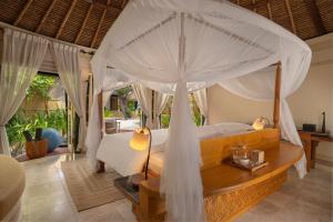 a bedroom with a large bed with a canopy at Banyan Tree Vabbinfaru in Male City