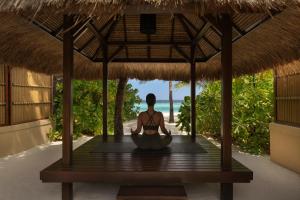 a woman sitting in a meditation pose in a hut at Banyan Tree Vabbinfaru in Male City