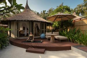 a woman sitting on a wooden deck with a gazebo at Banyan Tree Vabbinfaru in Male City