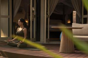 a woman sitting in a yoga pose on the floor at Banyan Tree Vabbinfaru in Male City +115 photos