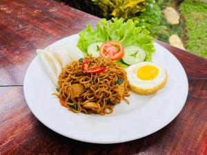a plate of food with noodles and an egg on a table at Gumitish Residence Singaraja in Singaraja