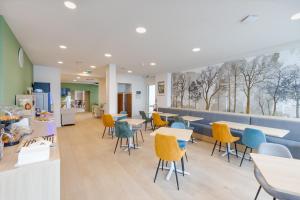 a cafeteria with tables and chairs and a counter at Karaez Hôtel - BritHotel Carhaix in Carhaix-Plouguer