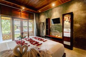 a bedroom with a bed with red roses on it at Puri Kurnia Ayu in Ubud