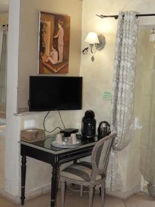 a desk with a television and a chair in a room at Le jardin de Saint Jean in Saint-Jean-aux-Bois