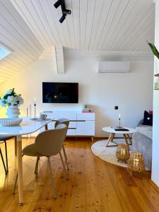 a living room with a dining table and a tv at Landhaus Wulfenia - APARTMENT KLAGENFURT - Private Sauna, Smart-TV, Air Conditioning, Free Parking in Klagenfurt