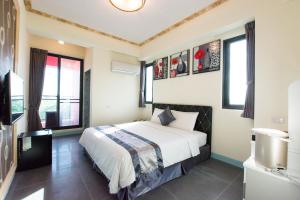 een slaapkamer met een bed en een aantal ramen bij Melinda Resort in Hengchun