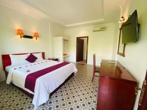 a bedroom with a bed and a flat screen tv at STC Hotel School in Phumĭ Réach Born (1)