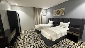 a hotel room with two beds and a television at Qimam Park Abha 4 in Abha