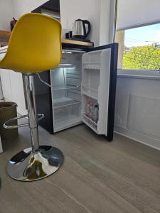 a yellow chair sitting in front of an open refrigerator at Studio M in Năsăud