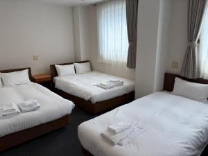 ein Hotelzimmer mit zwei Betten, auf denen Handtücher liegen in der Unterkunft Hotel Green Arbor in Sendai + 15 Fotos