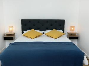 a bed with two yellow pillows and two lamps at Suite des Princes with Private Garden by La Boîte En Plus in Chantilly
