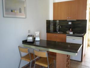 een keuken met een aanrecht met 2 stoelen en een wastafel bij Apartamentos Karina in Playa del Inglés