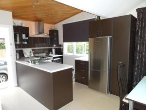 a kitchen with black cabinets and a stainless steel refrigerator at Thyme On The Terrace in Te Anau