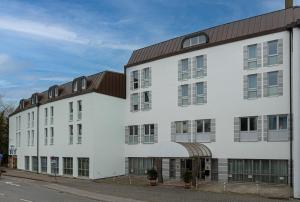 a white building with a brown roof at ibis Styles Rosenheim in Rosenheim