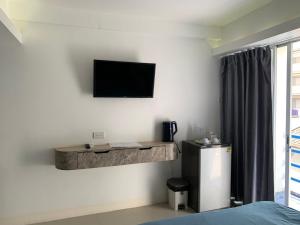 a room with a television on a wall with a refrigerator at say hi pattaya hotel in Pattaya +4 photos