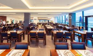 a restaurant with wooden tables and chairs and windows at Venezia Hotel and Suite in Yeosu