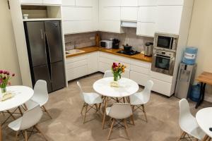 a kitchen with two white tables and white chairs at Fresh hostel in Almaty +16 photos