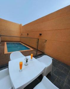 a balcony with two white tables and a swimming pool at فندق الراية الفندقية in Jazan