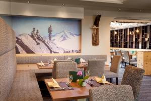 a dining room with tables and chairs and a large mural at Apartmenthaus Maximilian in Neukirchen am Großvenediger