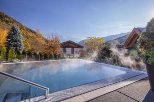 a swimming pool with mountains in the background at Hotel Ravelli Luxury Spa in Mezzana