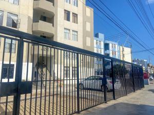 a fence with a car parked in front of a building at High Garden Apartment in Trujillo