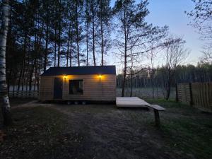 a small shed with a bench in a yard at Domek POD LASEM in Białowieża