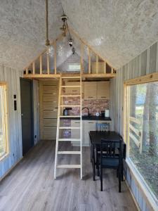 a tiny house with a loft bed and a table at Domek POD LASEM in Białowieża