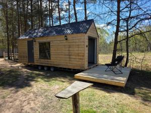 a wooden cabin with a chair on a wooden deck at Domek POD LASEM in Białowieża