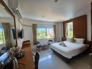 a bedroom with a bed and a desk and windows at SR Phuket in Patong Beach