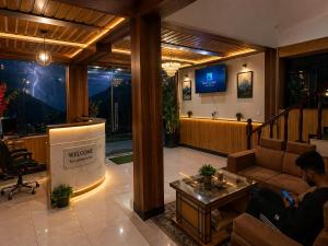 a man sitting on a couch in a lobby with a stage at Mountain Route Cottage in Manāli
