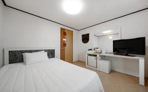a white bedroom with a bed and a television at Mo-A Motel in Sokcho