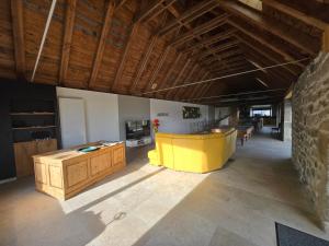 a large living room with a yellow table and wooden ceilings at Le Ché d'Aubrac in Nasbinals