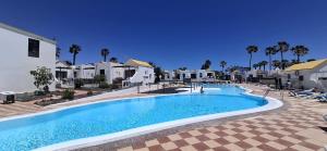 a pool at a resort with palm trees and houses at Alby House 2 Montecastillo in Caleta De Fuste