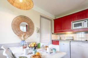 a kitchen with red cabinets and a table with fruit on it at L'Esquirou in Biscarrosse