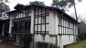 a white and black house with a balcony at L'Esquirou in Biscarrosse
