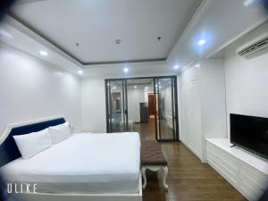 a bedroom with a white bed and a tv at Khách sạn QUEENIE in Hai Phong
