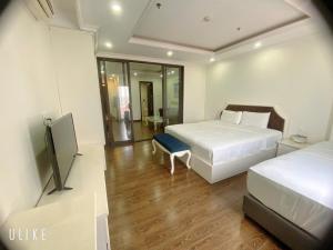 a bedroom with two beds and a flat screen tv at Khách sạn QUEENIE in Hai Phong