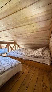 two beds in a room with a wooden ceiling at Osada Kryspinów in Cholerzyn
