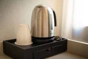 a coffeemaker sitting on a black stand next to a candle at Petit Palace Preciados in Madrid