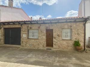 a stone house with two doors and a garage at La Pinela in Mesas de Ibor