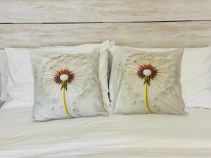 a bed with white pillows with two flowers on it at La Pinela in Mesas de Ibor