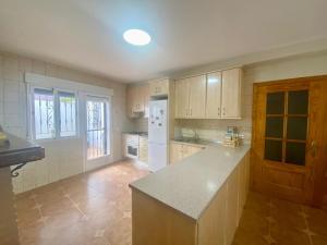 a kitchen with wooden cabinets and a white refrigerator at La Pinela in Mesas de Ibor +8 photos