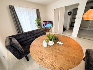 a living room with a wooden table and a couch at 新築一棟貸切 民宿 夢 駐車場2台無料 コンビニ徒歩2分 市街地へ好アクセス in Matsuyama