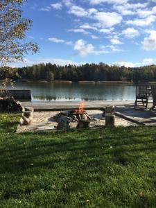 a fire pit next to a lake with a bench at kirsikkaranta 1 in Pargas