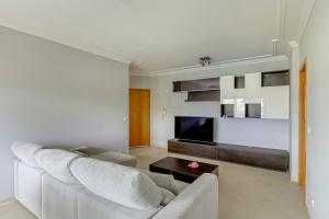 a living room with a white couch and a tv at 2-Bed Vialonga Vista Apartment in Lisbon